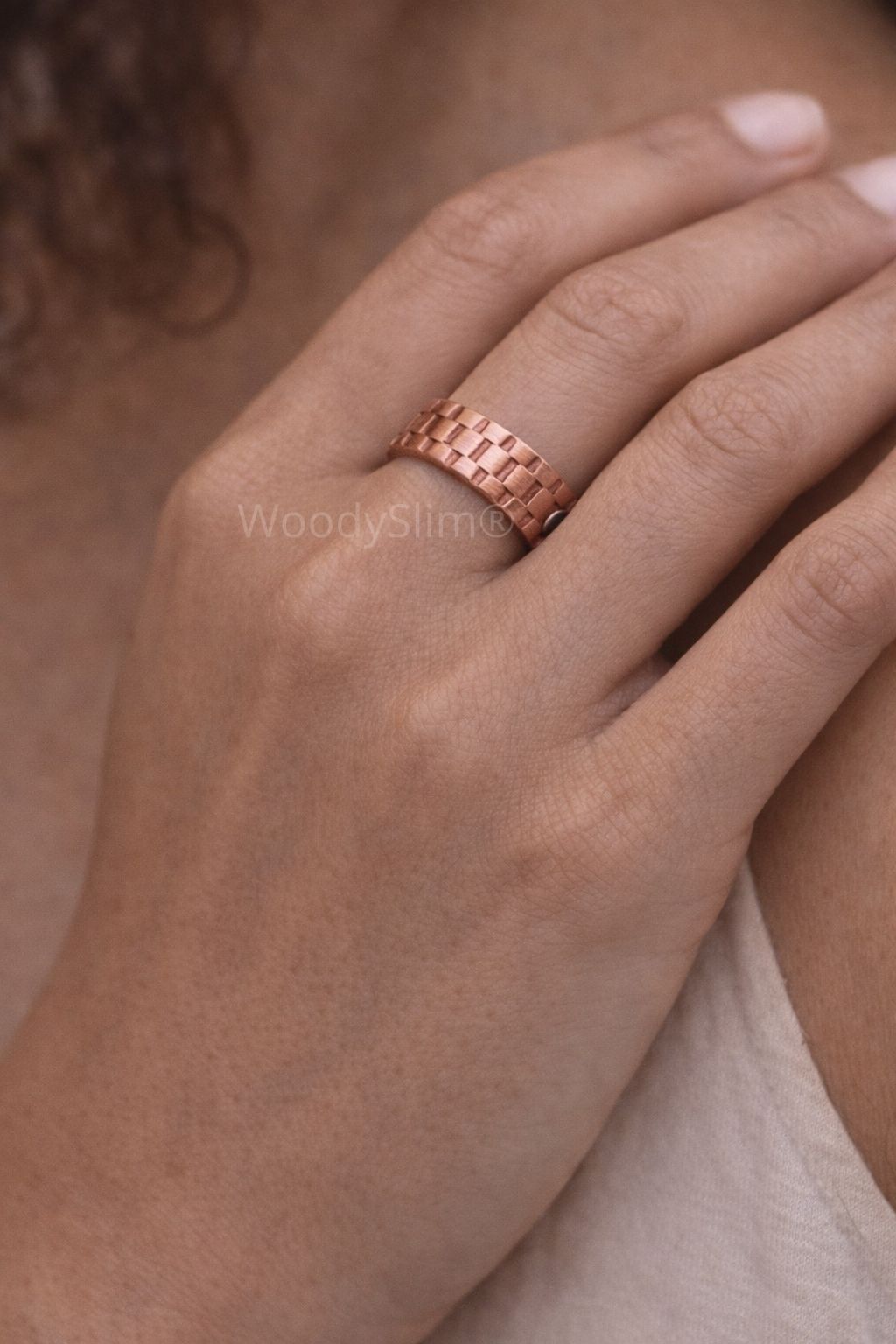 Gros plan d’une main féminine portant la bague magnétique en cuivre WoodySlim.