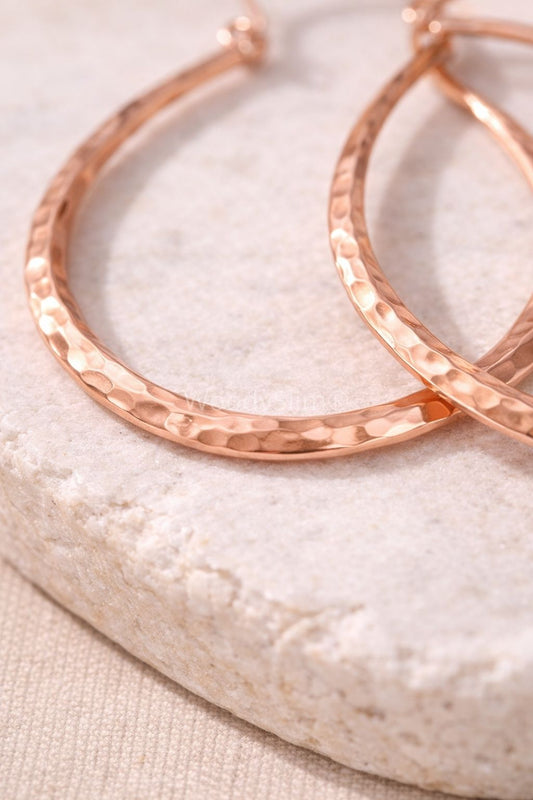 Détail de boucles d’oreilles en cuivre martelé avec texture irrégulière, finition rosée, bijou WoodySlim.