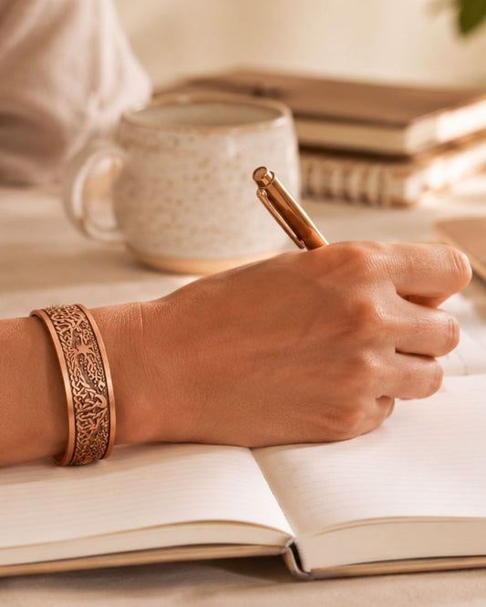 Femme portant un bracelet et une bague en cuivre WoodySlim, rituel bien-être du matin avec carnet et café