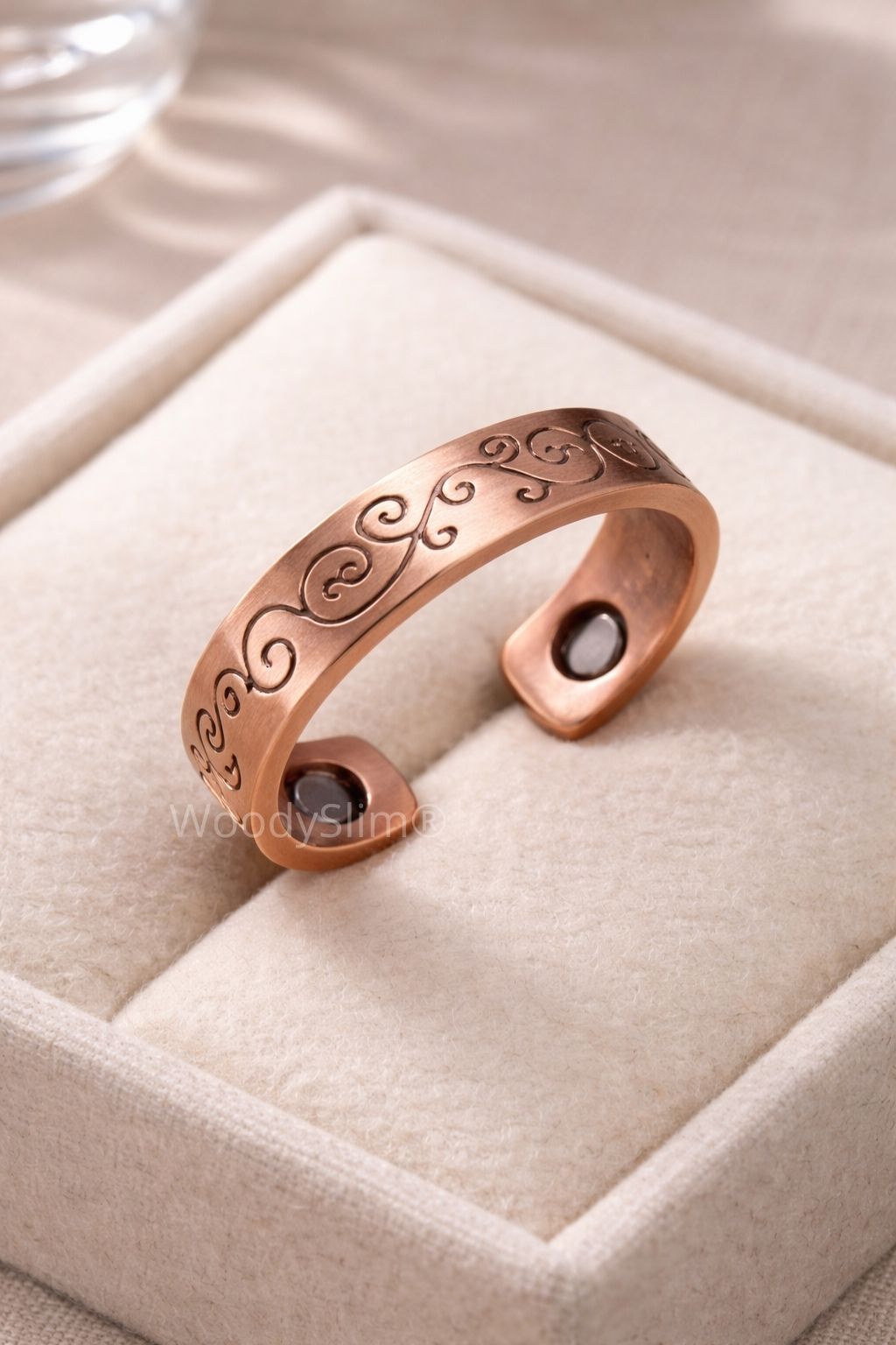Bague en cuivre gravée de motifs arabesques présentée seule sur un écrin clair, finition mate et design ouvert, bijou WoodySlim.