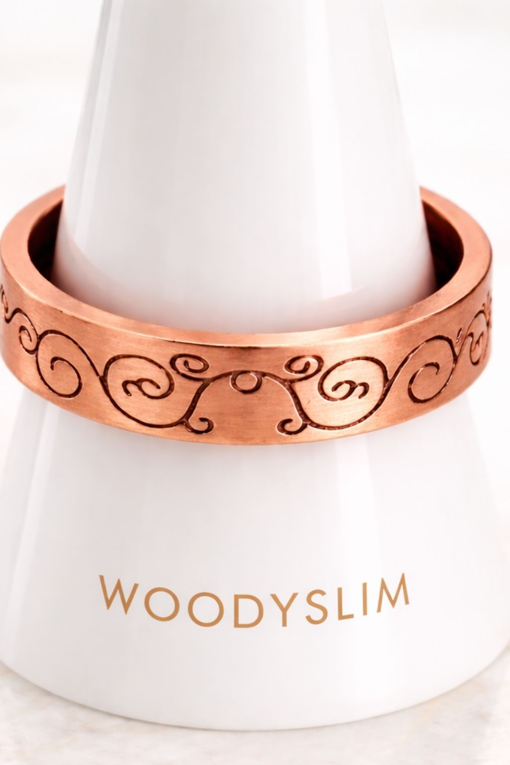 Bague en cuivre gravée motifs arabesques présentée sur un support blanc, largeur de l’anneau et détails visibles, bijou WoodySlim