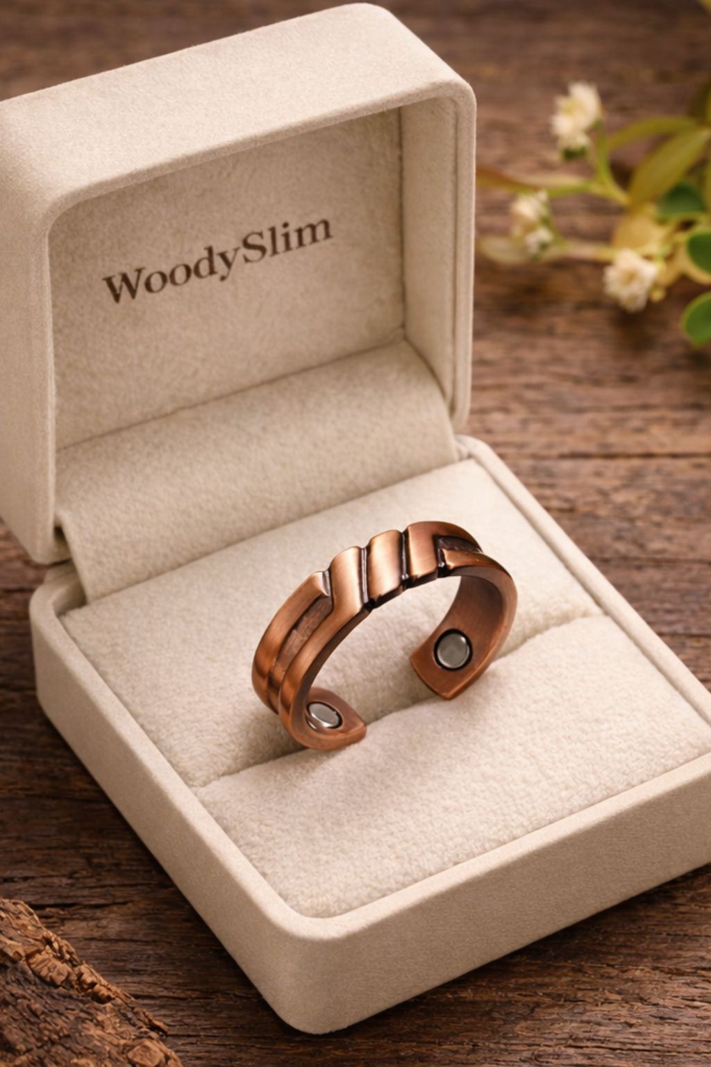 Gros plan d’une bague ouverte en cuivre magnétique WoodySlim®, finition brossée avec motif structuré et aimants visibles, présentée dans un écrin beige siglé WoodySlim