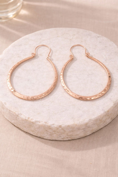 Paire de boucles d’oreilles créoles en cuivre martelé posées sur un socle clair, design circulaire et élégant, bijou WoodySlim.