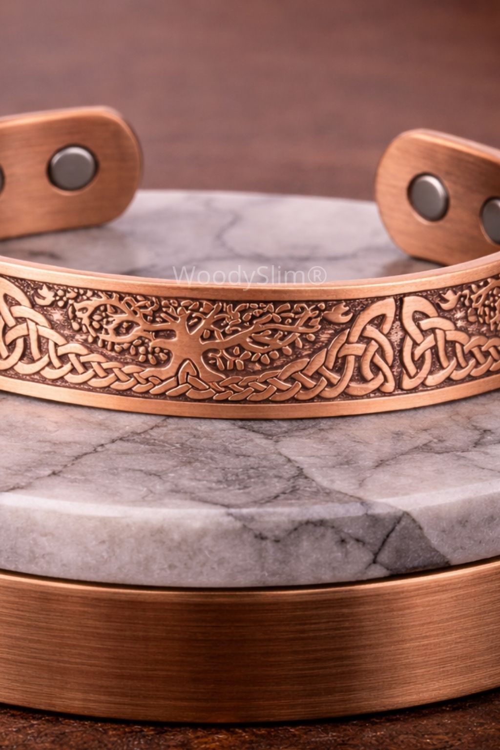 Bracelet en cuivre gravé avec motif arbre de vie et motifs géométriques, bracelet ouvert présenté sur un socle en pierre claire, bijou WoodySlim.