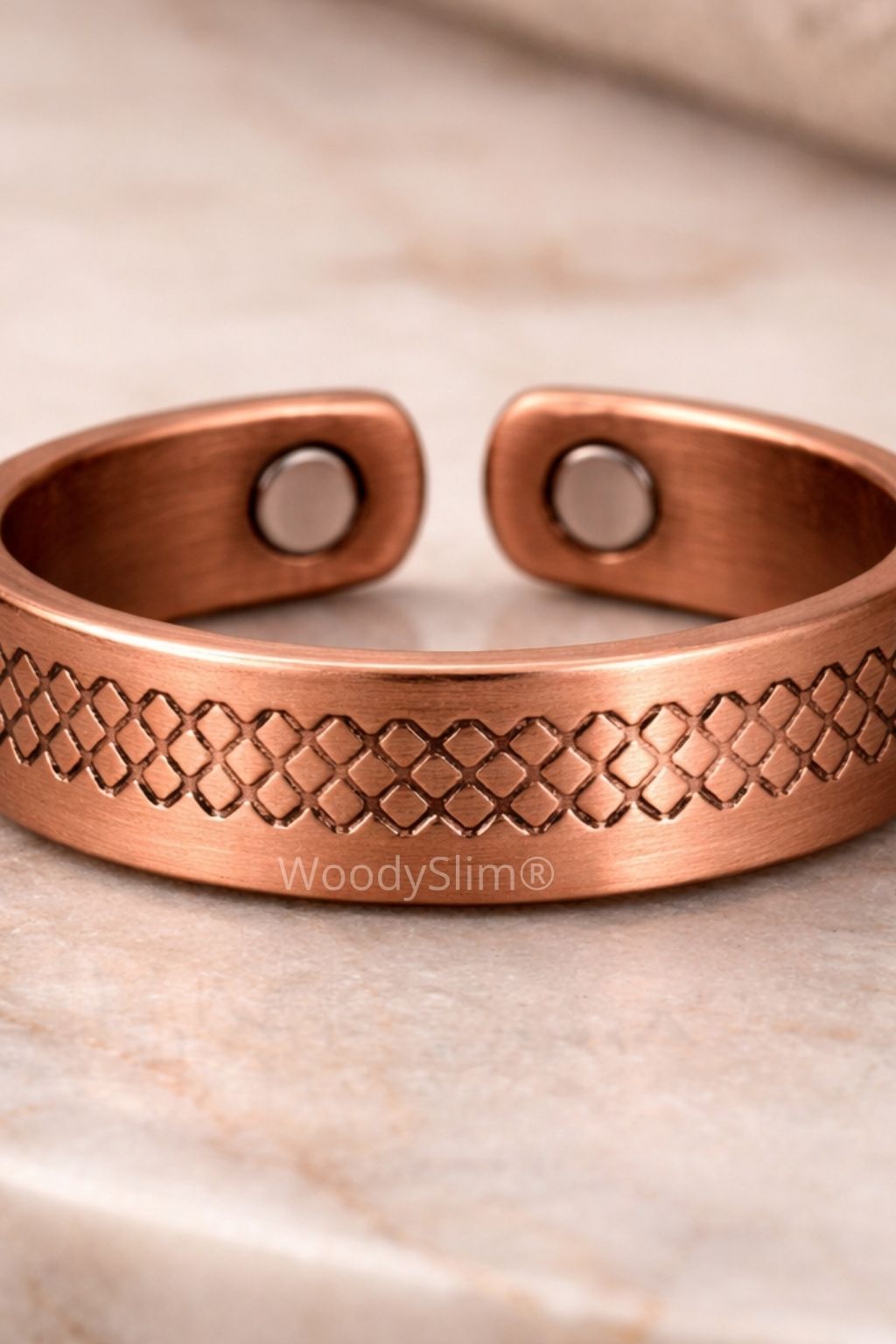 Bracelet en cuivre rigide ouvert avec motif tressé gravé et pastilles intérieures visibles, présenté sur un support clair, bijou WoodySlim.