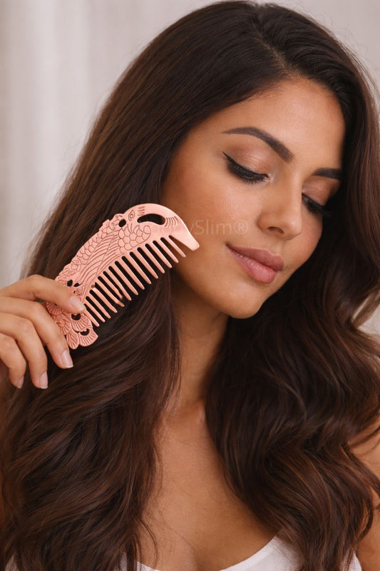 Femme tenant un peigne en cuivre gravé motif paon près de ses cheveux, accessoire élégant pour le coiffage WoodySlim.