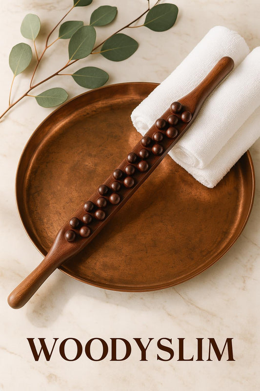 Scène bien-être avec rouleau de massage en bois et cuivre WoodySlim posé sur plateau cuivré, serviette blanche et feuilles eucalyptus.