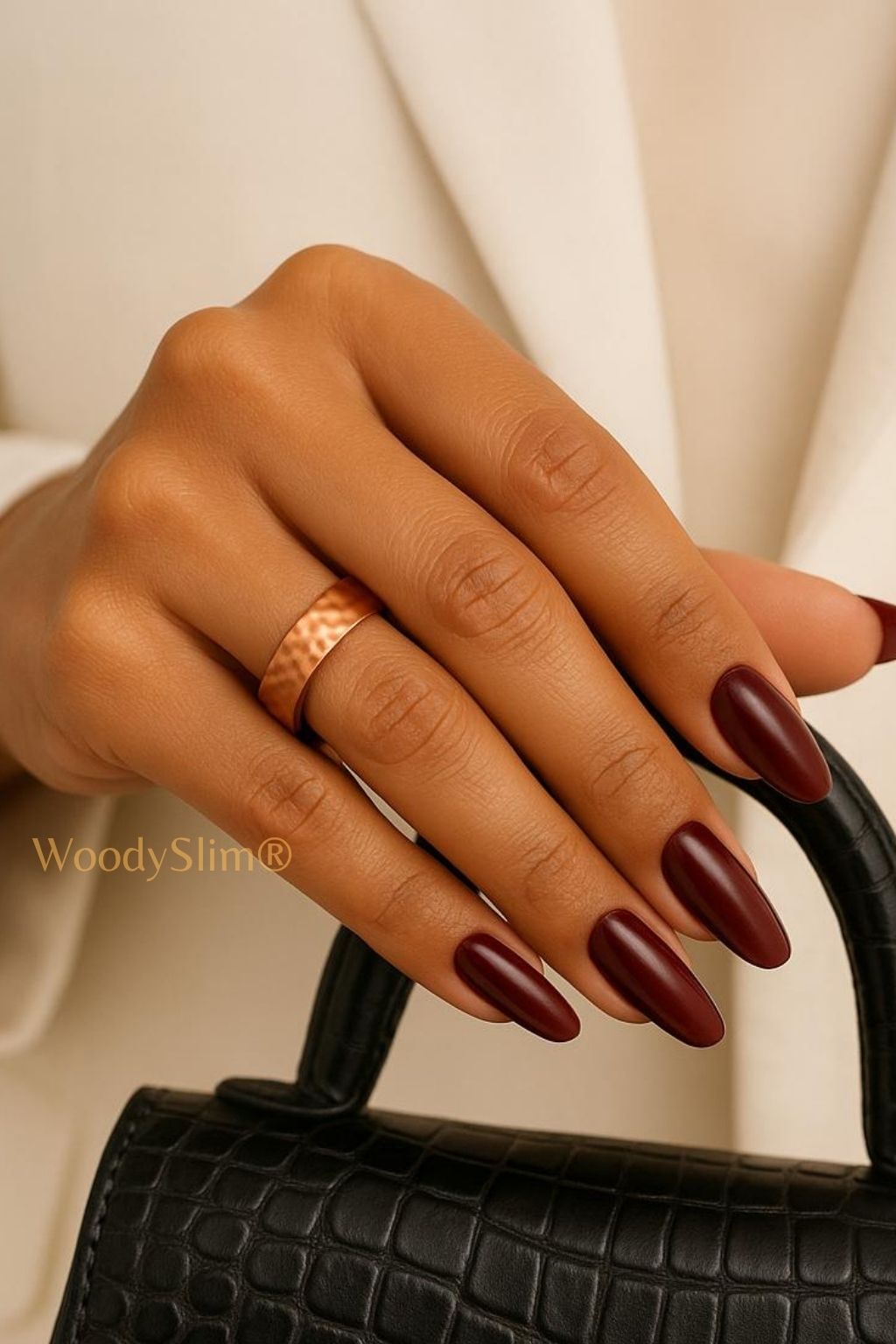 Bijoux en cuivre WoodySlim – main de femme, bague bien-être sur fond beige luxe et sac en cuir noir.
