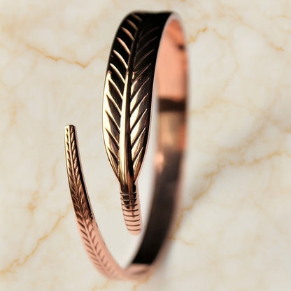 Bracelet ouvert en cuivre avec motif feuille gravée, bijou raffiné pour femme sur fond marbré clair, style naturel et élégant