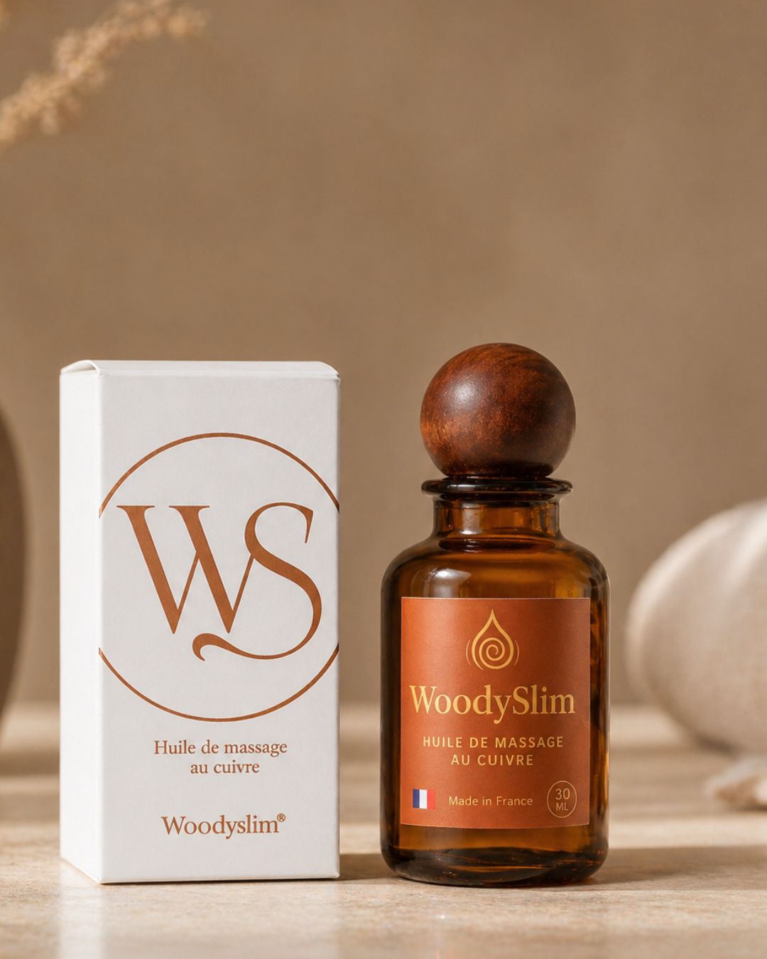 Flacon d’huile de massage au cuivre WoodySlim 30 ml en verre ambré avec étiquette blanche minimaliste et bouchon noir, accompagné de sa boîte assortie élégante, design épuré aux tons beige et cuivré, mise en scène haut de gamme sur fond neutre avec lumière douce.