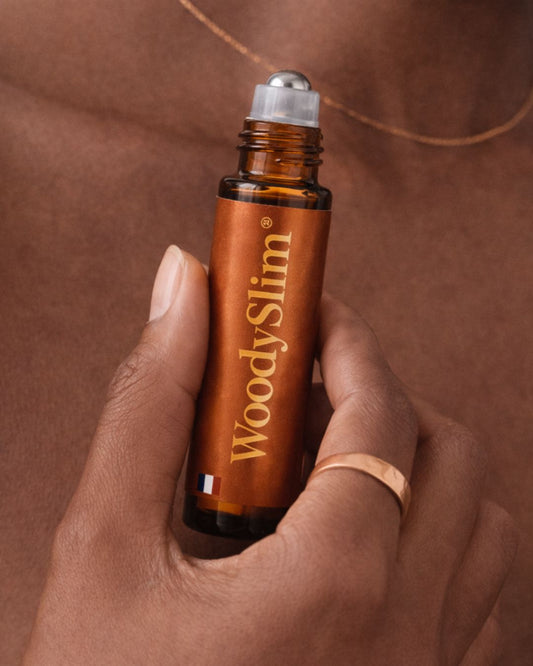 Roll-on WoodySlim à l’huile de rituel au cuivre tenu en main avec bijou en cuivre.