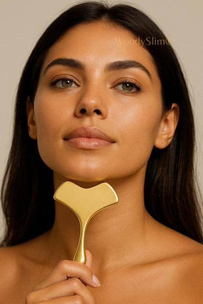 Accessoire visage WoodySlim – soin du cou et du visage avec gua sha en cuivre doré, femme au teint éclatant sur fond neutre haut de gamme.